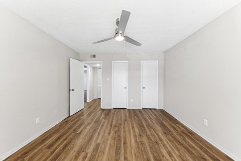 the spacious living room with wood flooring and a ceiling fan